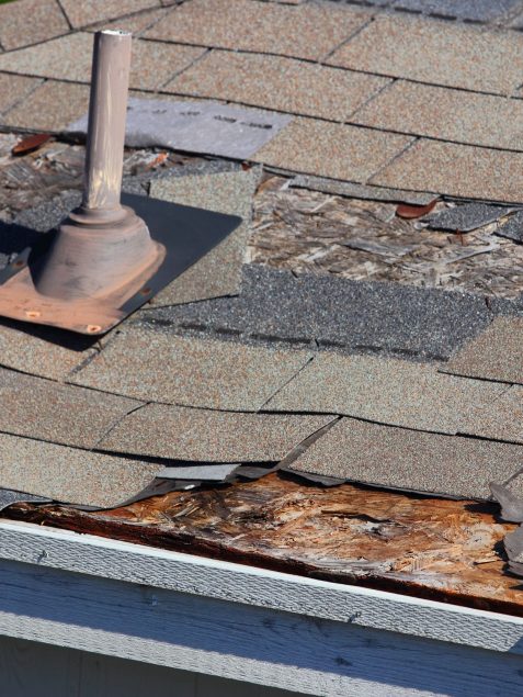 18035936 - a close up view of shingles being blown off a roof and other roof damage